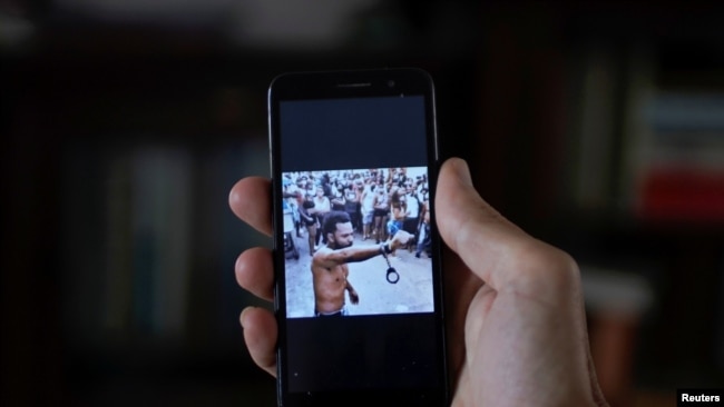 Un hombre muestra en su teléfono móvil una imagen que aparece en las redes sociales del rapero Maykel Osorbo con una mano esposada, en La Habana, Cuba, el 6 de abril de 2021. Foto tomada el 6 de abril de 2021. REUTERS /Alexandre Meneghini