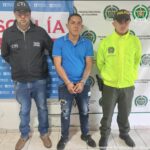 En la fotografía aparece Luis Eduardo Tapasco López junto a funcionarios del Cuerpo Técnico de Investigación (CTI) y la Policía Nacional y detrás tiene dos banner, uno con logos de la Policía y el otro de la Fiscalía.