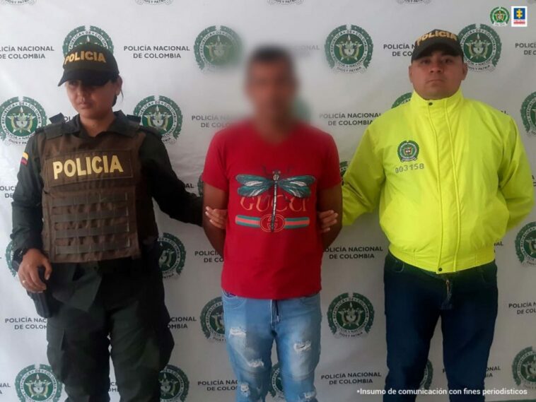 En la imagen se ve un hombre con camiseta roja capturado, en medio de un policía y un funcionario del CTI.