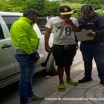 En la imagen se ve a una persona quien va a ser capturada por un policía y un funcionario del CTI, junto a una camioneta.