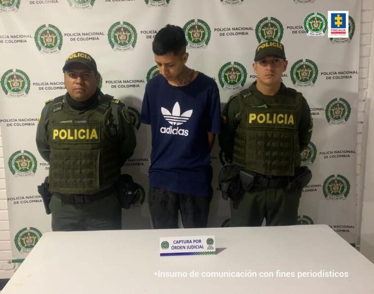 En la fotografía aparece un hombre capturado, junto a dos agentes de la Policía Nacional. En la parte posterior de la imagen se ve un banner de la Policía Nacional