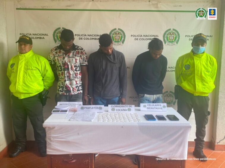 En la fotografía aparecen los tres hombres capturados, junto a agentes de la Sijin de Policía Nacional. En la parte superior se observa un banner de la Policía Nacional