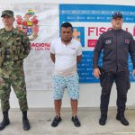 En la fotografía aparece un capturado junto a personal de Fiscalía General de La Nación y  Ejército  Nacional. En la parte posterior de la imagen se ven banners de Ejército Nacional y la Fiscalía General de la Nación.