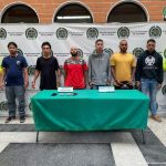 En la imagen se encuentran los 7 procesados con un pendón de la Policía Nacional al fondo y dos uniformados en ambos lados