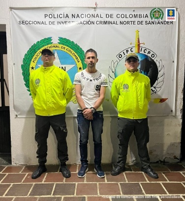 En la imagen se observa el capturado junto a uniformados de la Policía Nacional. En la parte posterior se encuentra un banner del Departamento de Policía de Norte de Santander