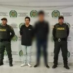 Hombre capturado que viste camiseta negra y Jeans azul claro, en posición de pie, con las manos atrás y en el medio de dos funcionarios de la Policía Nacional.