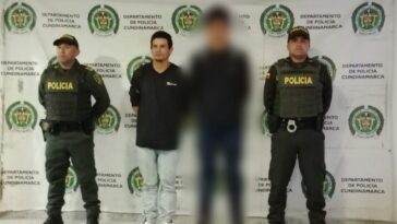 Hombre capturado que viste camiseta negra y Jeans azul claro, en posición de pie, con las manos atrás y en el medio de dos funcionarios de la Policía Nacional.