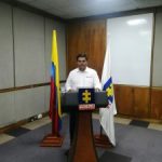 En la fotografía se observa a un funcionario de la Fiscalía leyendo el acta de entrega oficial de los restos de una víctima detrás de un atril, acompañado por las banderas de la Fiscalía General y de Colombia.