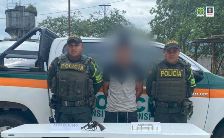 En las fotografía aparece un capturado junto a personal de Policía Nacional. En la parte posterior de la imagen se ven banners de Policía Nacional y la Fiscalía General de la Nación.