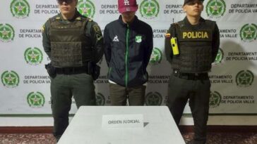 En la foto aparecen de pie y con los brazos atrás, José Ignacio Vélez Alzate. Viste con buzo oscuro con cierre verde y dos estampados a la altura del pecho; pantalón verde y gorra vinotinto. A lado y lado de él hay uniformados de la Policía Nacional. Delante de ellos hay una mesa blanca con un letrero que dice: ‘orden judicial’. Detrás de ellos hay un pendón institucional de la Policía.