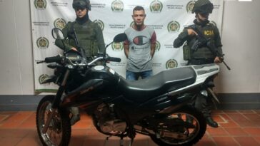 En la fotografía se aprecia el capturado entre dos uniformados de la Policía Nacional, al frente la motocicleta recuperada. En la parte posterior se observa el banner de la Policía Nacional.