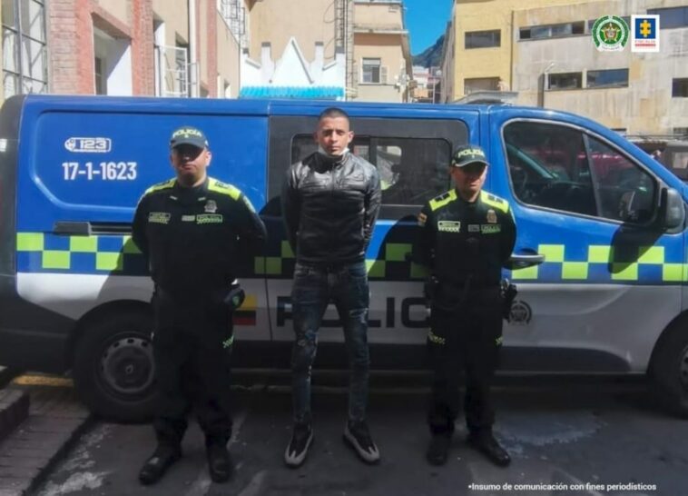 En la fotografía se observa al capturado junto a dos agentes de la Policía Nacional.   En la parte superior se observa una radiopatrulla de la Policía