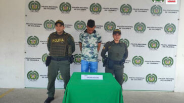 El capturado aparece esposado junto a dos uniformados de la Policía.
