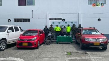 En la foto aparece, de pie alias ‘El Flaco’ y a lado y lado del él hay uniformados de la Policía y Ejército Nacional. Delante de ellos hay una mesa con mantel verde y sobre ella se parecía munición, armas de fuero y otros elementos. Asimismo, al lado derecho de ellos hay una camioneta blanca doble cabina y platón; un automóvil rojo y una motocicleta. Al lado izquierdo de ellos hay un vehículo otro rojo. Detrás de ellos hay un pendón institucional de la Policía.