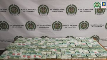 Fotografía de dinero incautado, el cual está organizado sobre una mesa y distribuido en varios fajos de billetes de 100.000 pesos.