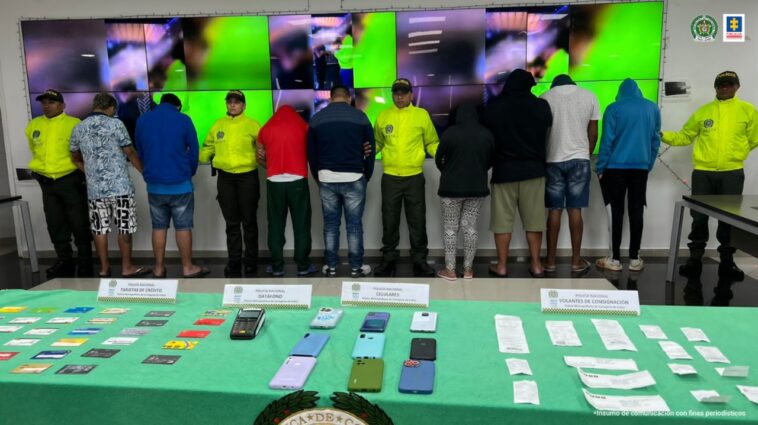 En la imagen se aprecian ocho personas capturadas, entre cuatro uniformados de la Policía y frente a una mesa con objetos incautados.