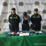 En la fotografía se aprecia a la procesada esposada, custodiada por dos uniformados de la Policía Nacional. Está en una mesa con los 38 celulares que habría hurtado la mujer durante un evento del Carnaval de Barranquilla.