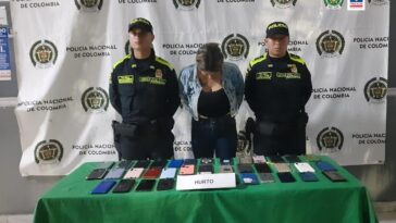 En la fotografía se aprecia a la procesada esposada, custodiada por dos uniformados de la Policía Nacional. Está en una mesa con los 38 celulares que habría hurtado la mujer durante un evento del Carnaval de Barranquilla.