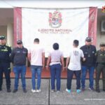 En la fotografía aparecen tres capturado, junto a personal de Fiscalía General de La Nación, Policía Nacional y Ejército Nacional. En la parte posterior de la imagen se ven banners de Ejército Nacional, Policía Nacional y la Fiscalía General de la Nación.