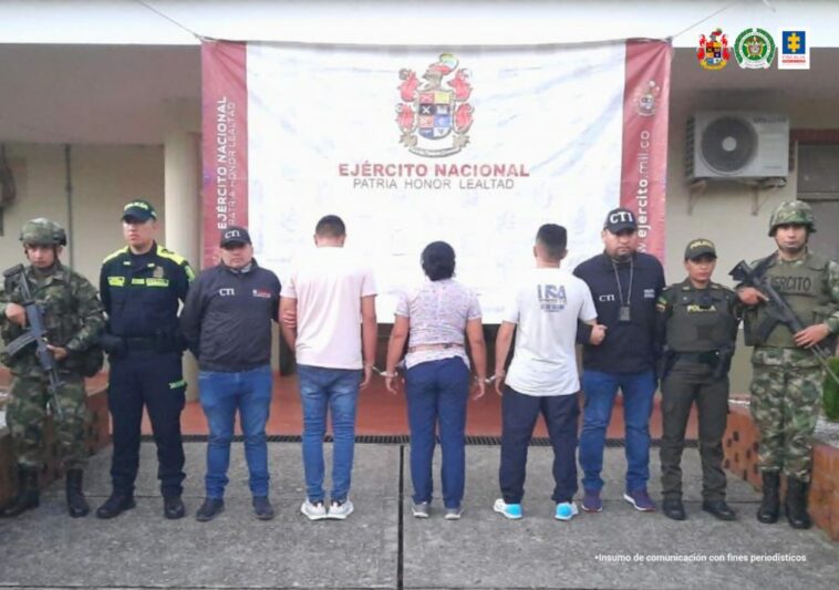 En la fotografía aparecen tres capturado, junto a personal de Fiscalía General de La Nación, Policía Nacional y Ejército Nacional. En la parte posterior de la imagen se ven banners de Ejército Nacional, Policía Nacional y la Fiscalía General de la Nación.