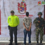 En la fotografía se observa al capturado de espaldas junto a uniformados de la Policía y el Ejército Nacional. En la parte posterior se aprecia el banner que identifica al Ejército Nacional