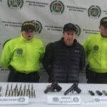 En la fotografía se observa al capturado junto a dos agentes de la Sijin de la Policía Nariño. En la parte posterior se observa una mesa con dos pistolas, 4 proveedores, munición y un teléfono celular