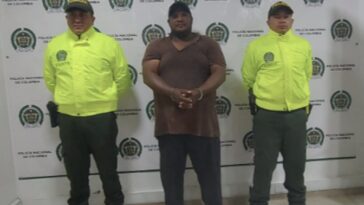 en la foto el hmbre de camisa oscura con esposas acompañado de dos uniformados de la policóa Nacional