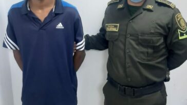 En la fotografía se observa a un hombre moreno con las manos atrás, de camiseta azul oscura con blanca y bermuda blanca, custodiado por un agente de la Policía Nacional.