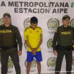 En la fotografía aparece un capturado, junto a personal de Policía Nacional. En la parte posterior de la imagen se ven banners de Policía Nacional y la Fiscalía General de la Nación.