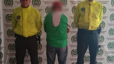 n la fotografía se aprecia el capturado de espaldas junto a dos uniformados de la Policía Nacional. En la parte posterior se observa el banner que identifica al Departamento de Policia Arauca