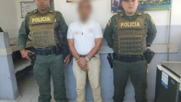 En la imagen se observa a un hombre con camiseta blanca y pantalón beis, custodiado por dos agentes de la Policía Nacional.
