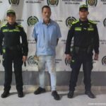 El procesado tiene una camisa blanca y está esposado. Uniformados de la Policía Nacional lo custodian.