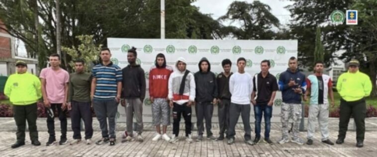 En la imagen se encuentran los 12 detenidos por tráfico de estupefacientes, acompañados por dos agentes de policía