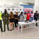 En la fotografía se aprecian los seis capturados junto a un investigador del CTI y uniformados de la Policía y Ejército Nacional. Frente a ellos una mesa con los elementos incautados. En la parte posterior los banners que identifican a la Fiscalía General de la Nación y a la Policía Nacional.