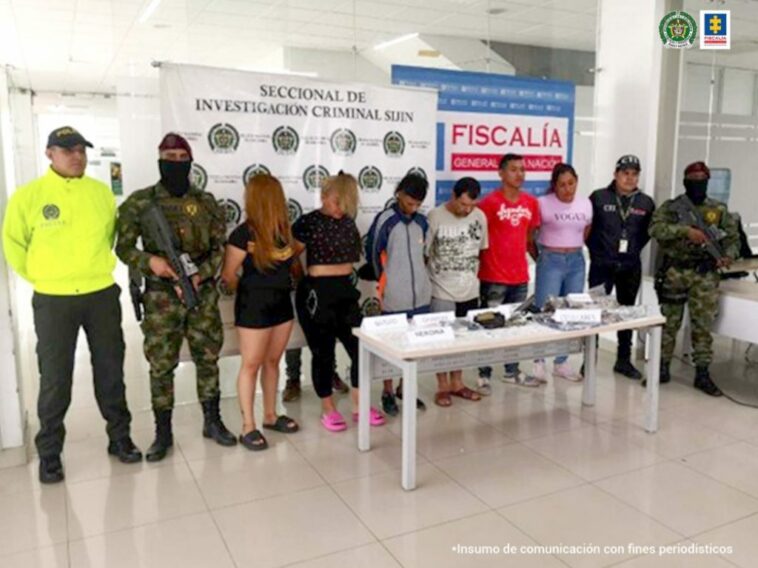 En la fotografía se aprecian los seis capturados junto a un investigador del CTI y uniformados de la Policía y Ejército Nacional. Frente a ellos una mesa con los elementos incautados. En la parte posterior los banners que identifican a la Fiscalía General de la Nación y a la Policía Nacional.