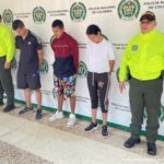 En la fotografía aparecen tres capturados, junto a personal de Policía Nacional. En la parte posterior de la imagen se ven banners de Policía Nacional y la Fiscalía General de la Nación.