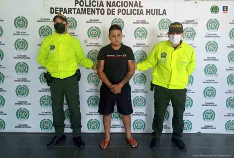 En la fotografía aparecen un capturado, junto a personal de Policía Nacional. En la parte posterior de la imagen se ven banners de Policía Nacional y la Fiscalía General de la Nación.