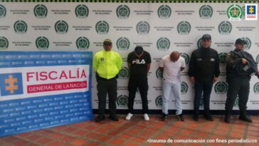 Se observa a dos capturados de frente.  A un lado un funcionario del CTI y en el otro uno de Policía Nacional.  Al fondo backing de Policía Nacional