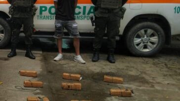En la fotografía se observa el capturado junto a dos agentes de la Policía Nacional. En la parte posterior se observan 12 paquetes rectangulares que contenían clorhidrato de cocaína