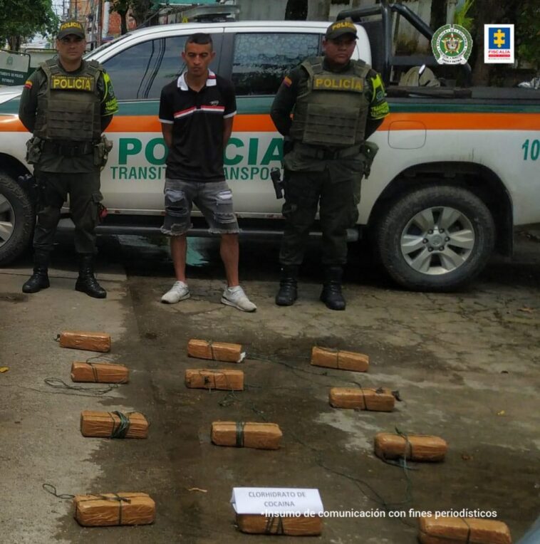 En la fotografía se observa el capturado junto a dos agentes de la Policía Nacional. En la parte posterior se observan 12 paquetes rectangulares que contenían clorhidrato de cocaína