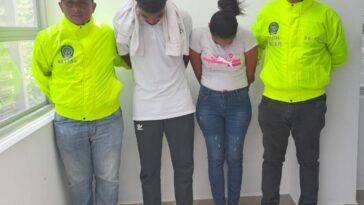 En la imagen se observa a un hombre vestido de camiseta blanca y sudadera gris y a una mujer de camiseta blanca con jean, ambos de frente pero con la cabeza agachada, custodiado por dos agentes de la Policía Nacional.