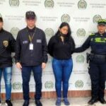 En la imagen se ve una mujer detenida bajo custodia de funcionarios del CTI, Policía Nacional y Gaula Militar. Detrás suyo un backing de la Policía.