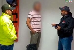 En la imagen se ve una persona detenida frente a un investigador que le lee sus derechos y junto con un policía.