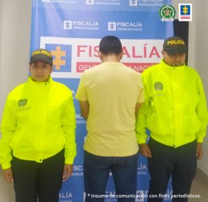 En la fotografía se aprecia al capturado de espaldas junto a dos uniformados de la Policía Nacional. En la parte posterior el banner que identifica a la Fiscalía