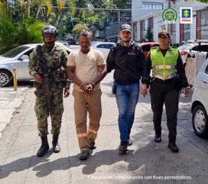 En la fotografía aparece en una vía pública, en acción de caminata, con los brazos adelante y esposado, Francis Wayler Urrutia Rivas. Viste camiseta de manga corta color beage y pantalón caqui. A lado izquierdo de él hay un servidor del CTI de la Fiscalía y una uniformada de la Policía Nacional. Al lado derecho hay un uniformado del Ejército Nacional.