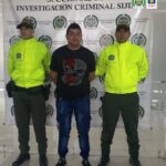 En la imagen se aprecia el capturado junto a uniformado de la Policía. En la parte posterior se observa el banner que identifica a la Seccional de Investigación Criminal Sijin de la Policía Nacional.