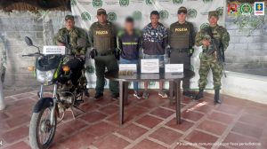 En la imagen aparecen dos personas capturadas, entre cuatro uniformados de la Policía y frente a una mesa que contiene munición de fusil.