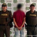 En la imagen aparece el capturado de espaldas junto a dos uniformados de la Policía Nacional. En la parte posterior se aprecia el banner que identifica a la Policía Nacional en Arauca
