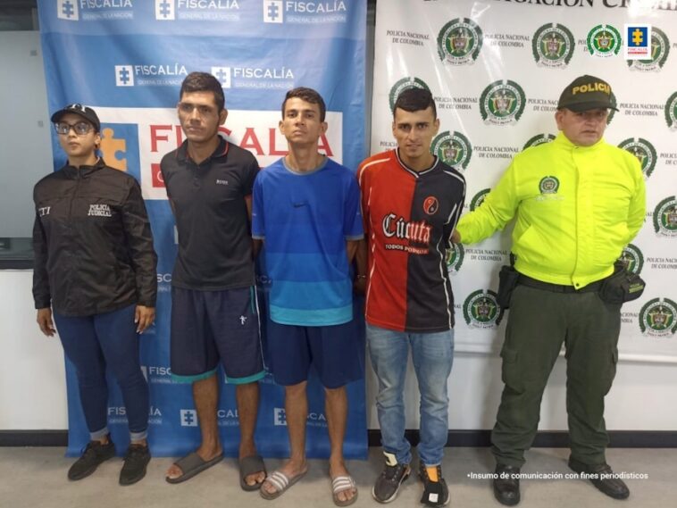 En la imagen se aprecia los tres capturados, junto a una investigadora del CTI y un uniformado de la Policía Nacional. Detrás de ellos los banners que identifican a la Fiscalía General de la Nación y a la Policía Nacional.