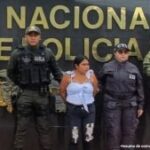 En la imagen se ve una mujer detenida bajo custodia de integrantes de la Policía Nacional.